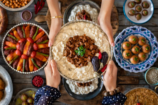 many kinds of food at the hands of family members. local foods named hünkar beğendi or hunkar begendi . i̇ftar concept. - lebanese culture imagens e fotografias de stock