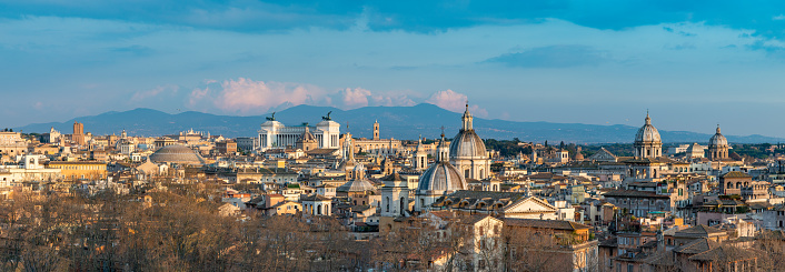 A panorama picture of the landmarks and rooftops of Rome at sunset.
