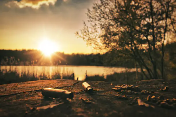 hunting ammunition lies on a wooden table by the lake at sunset