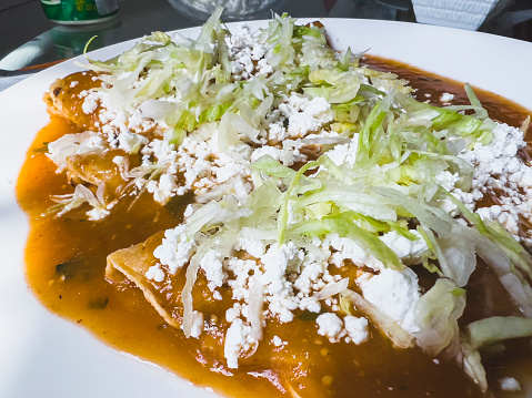 Close up of red enchiladas with cheese and lettuce