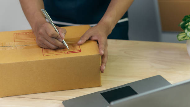 istock Start a business by writing an address on a box and taking orders from customers with a laptop at home preparing parcels in the SME supply chain. Online Purchasing. or coronavirus quarantine concept 1389307438