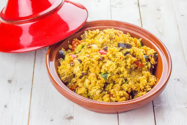 Traditionally orepared meal in the moroccan tagine with couscous, vegetables and dried fruit on a white table