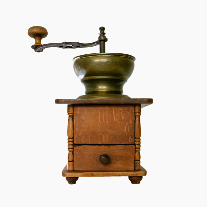 Grinding coffee beans in a manual coffee grinder on a wooden table. Copy space
