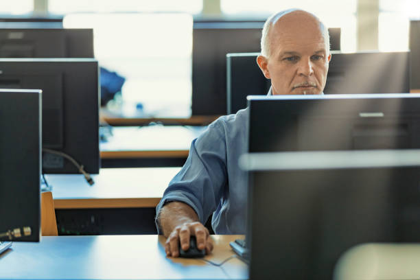 istock middle-aged man uses a desktop PC workstation in a common room 1389310120