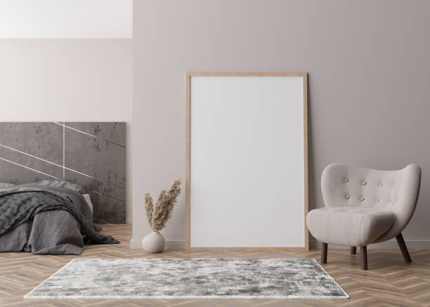 istock Empty vertical picture frame standing on parquet floor in modern bedroom. Mock up interior in contemporary style. Free space for picture or poster. Bed, armchair, pampas grass. 3D rendering. 1389314445