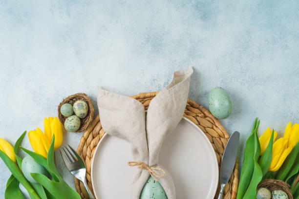 istock Easter festive table setting with easter eggs decoration and yellow tulips flowers on gray background. Top view, flat lay 1389314533
