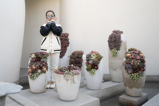 woman posing in front of succulents in a white vase