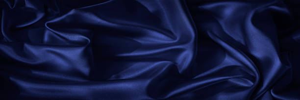 istock Black blue silk, satin. Shiny fabric surface. Beautiful wavy folds. Dark elegant background with space for design. web banner. 1389319548