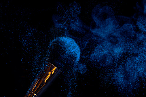 make-up brush with powder of different colors on a dark background like space dust best in Ukraine