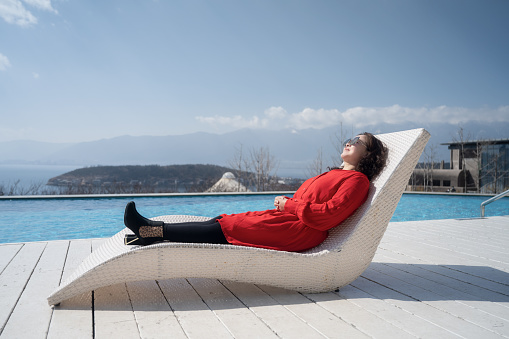 woman in red, sunning herself on a chair by the pool