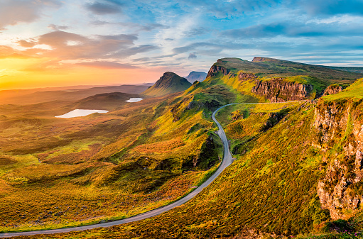 Long winding road at Quiraing on the Isle of Skye with a beautiful vibrant sunrise sky.