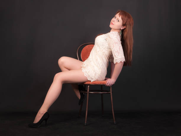 studio portrait of a girl in a white dress on a chair