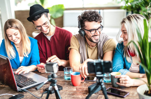 istock Young happy students sharing content on streaming platform with digital web cam - Modern life style concept with millenial guys and girls having fun vlogging live feeds on social media - Vivid filter 1389331248