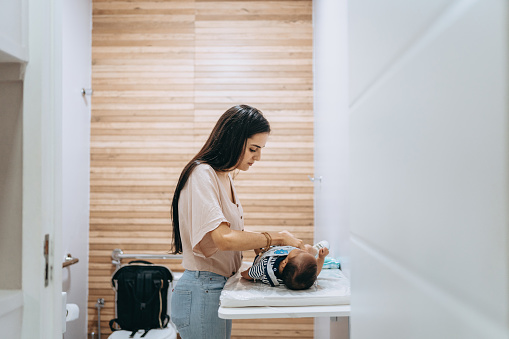 Mother changing baby's diapers on changing table