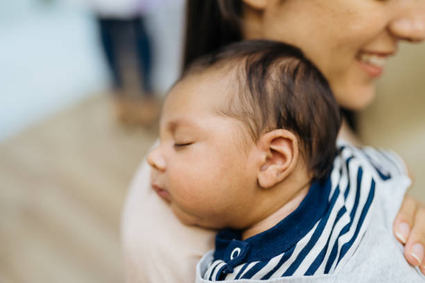 istock Smiling mother with newborn baby on shoulder 1389331348