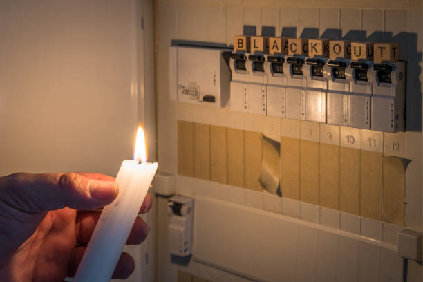 istock Fuse box with fuses in a distribution box during a power outage lit with white candle holding a man with the word blackout as text, Germany 1389332306