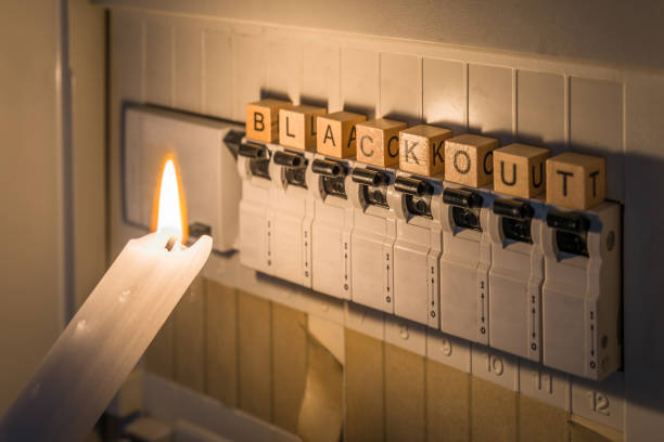 Fuse box with fuses in a distribution box during a power outage lit with white candle holding a man with the word blackout as text, Germany Fuse box with fuses in a distribution box during a power outage lit with white candle holding a man with the word blackout as text, Germany blackout stock pictures, royalty-free photos & images