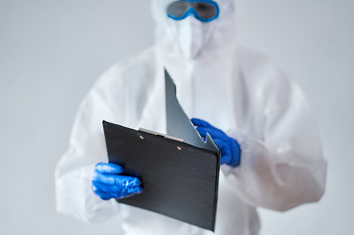 Portrait of a worker with full protective suit holding a folder