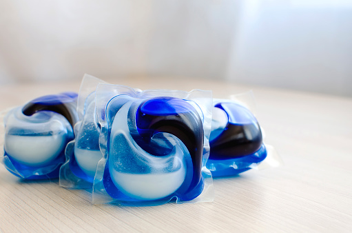 Washing gel capsule pod with laundry detergent on neutral background. Place for text, copyspace.