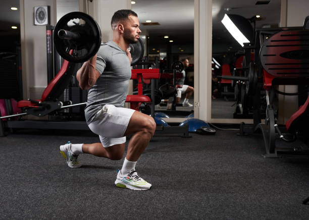 Man doing lunges with barbell stock photo