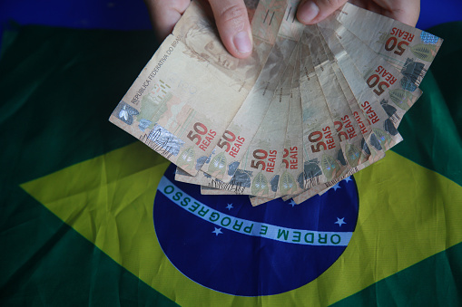 salvador, bahia, brazil - april 3, 2022: fifty reais banknotes next to a brazil flag.