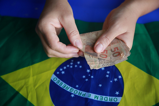 salvador, bahia, brazil - april 3, 2022: fifty reais banknotes next to a brazil flag.