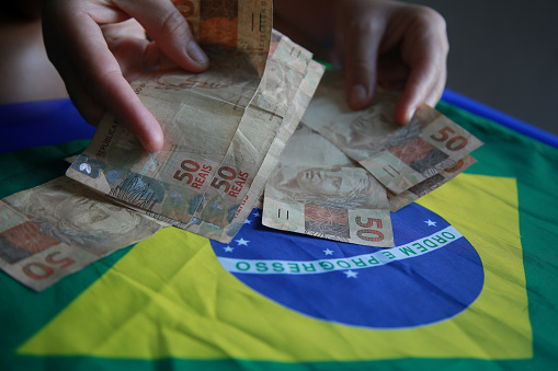 salvador, bahia, brazil - april 3, 2022: fifty reais banknotes next to a brazil flag.