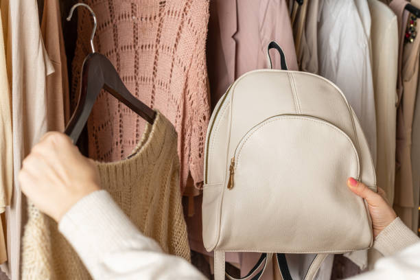 istock Woman choosing  small leather backpack, clothes in home cupboard. Season concept 1389334880