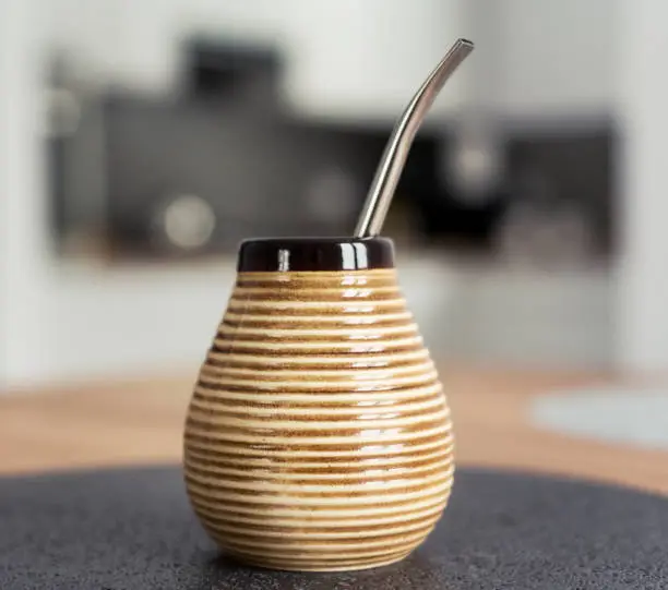 Traditional South American Yerba Mate tea in matero cup with bombilla metal straw servin photographed in modern kitchen