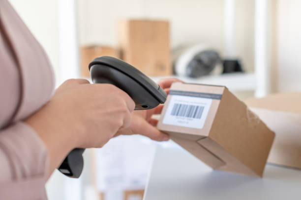 istock Woman employee of post office scanning parcel using barcode scanner to confirm sending customer. Home delivery service. 1389335070
