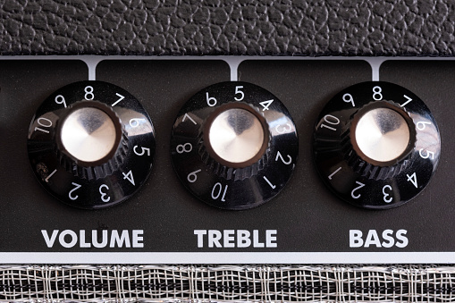 detail of the volume, treble and bass control knobs of a guitar amplifier, equalization dials close up, selective focus horizontal