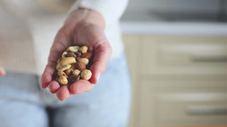 Nuts spilling from jar in woman's hand