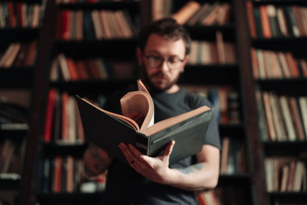 istock Adult student reading a book in the college library 1389338580