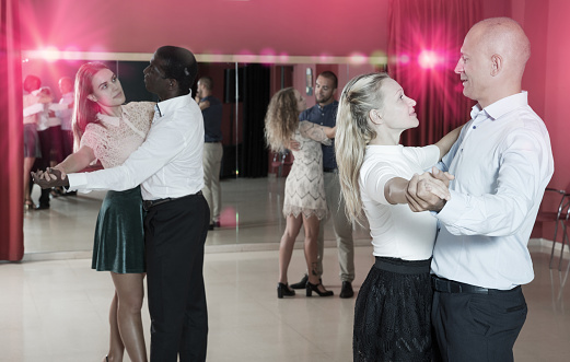 Young smiling people learning to dance waltz in dancing class