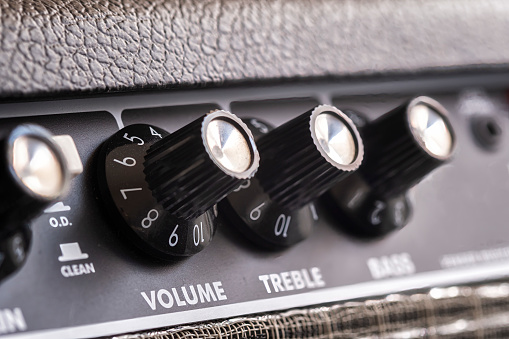 selective focus of the volume, treble and bass control knobs of a guitar amplifier, equalization dials close up, vertical