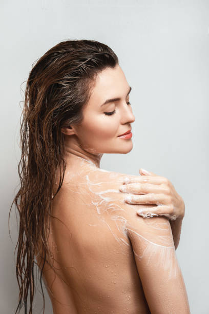 Beautiful woman washing her body with shower gel stock photo