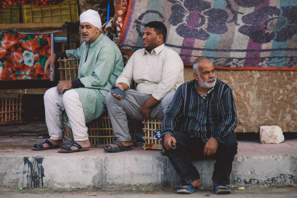 un petit groupe d’hommes égyptiens locaux assis et attendant le bus dans le centre siwa oasis - women indigenous culture middle east traditional culture photos et images de collection