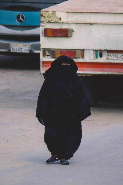 femme égyptienne locale en robe noire traditionnelle marchant dans la rue siwa oasis - women indigenous culture middle east traditional culture photos et images de collection