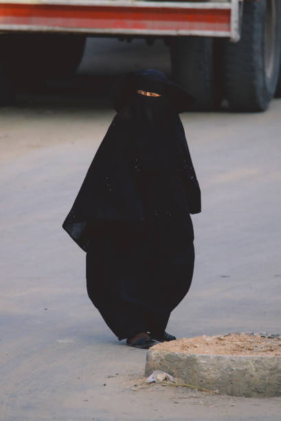 femme égyptienne locale en robe noire traditionnelle marchant dans la rue siwa oasis - women indigenous culture middle east traditional culture photos et images de collection