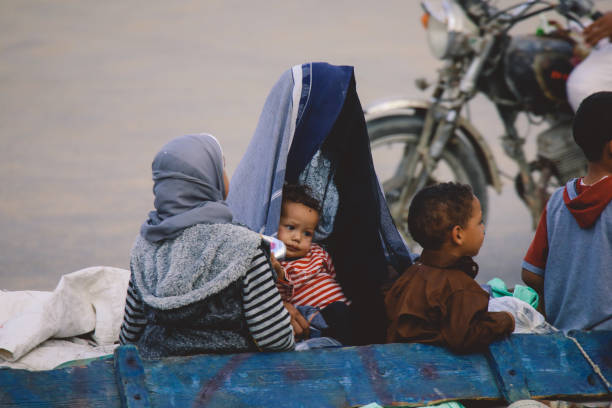 femmes égyptiennes locales en robes traditionnelles grises et noires à l’arrière du pousse-pousse bleu sur les routes de l’oasis de siwa - women indigenous culture middle east traditional culture photos et images de collection