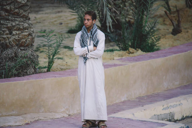 jeune homme égyptien local en robe blanche traditionnelle debout dans le centre-ville de l’oasis de siwa - women indigenous culture middle east traditional culture photos et images de collection