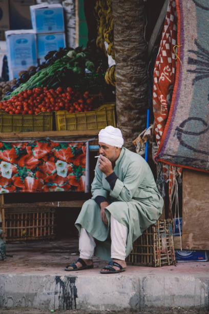 vieil homme égyptien local à barbe blanche en bonnet blanc assis près de la boutique dans le centre-ville de l’oasis de siwa - women indigenous culture middle east traditional culture photos et images de collection