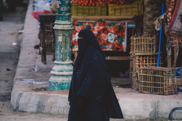 femme égyptienne locale en robe noire traditionnelle marchant dans la rue siwa oasis - women indigenous culture middle east traditional culture photos et images de collection