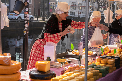 Alkmaar, The Netherlands, March 25, 2022; Female cheese sellers with traditional clothing on a market stall at the Alkmaar cheese market.