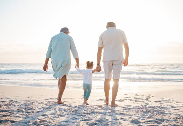 снимок пожилой пары на пляже с очаровательной внучкой - grandparent grandfather walking grandchild стоковые фото и изображения
