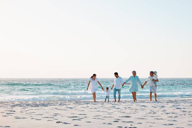 aufnahme einer mehrgenerationenfamilie, die zeit zusammen am strand verbringt - family grandmother multi generation family nature stock-fotos und bilder