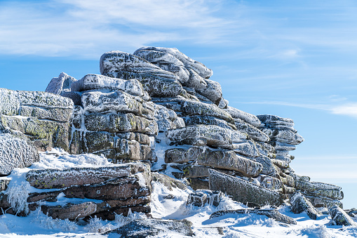 Rocks frozen and covered with snow on a sunny day with blue sky in the background