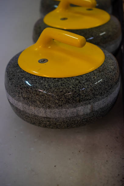 istock Close-up of a curling stone with a yellow handle stands on ice. 1389346043