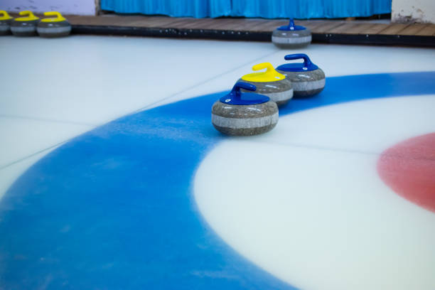 istock A yellow-handled stone stands between two blue-handled curling stones on the blue circle of the House. 1389346051