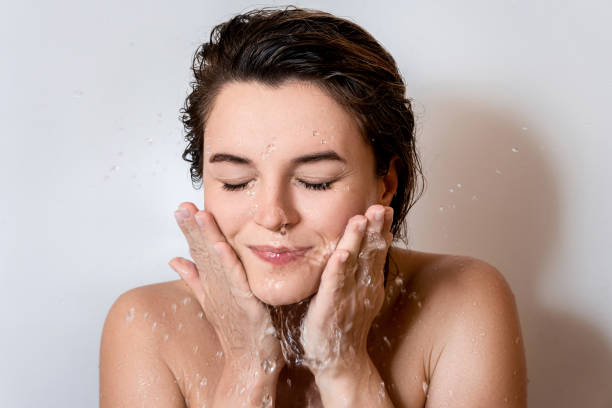 Young woman washing her face with clean water stock photo